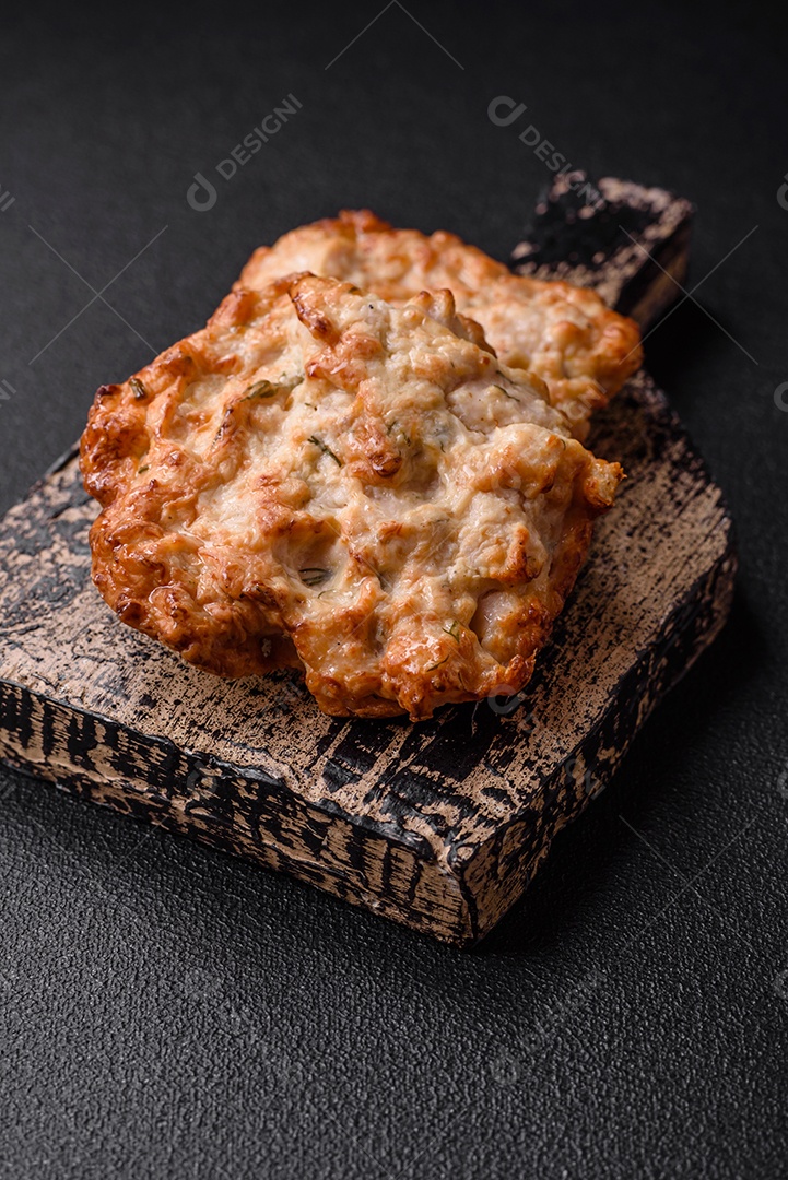 Deliciosa costeleta de frango frito ou carne de porco frita à milanesa com sal, especiarias e ervas sobre um fundo escuro de concreto