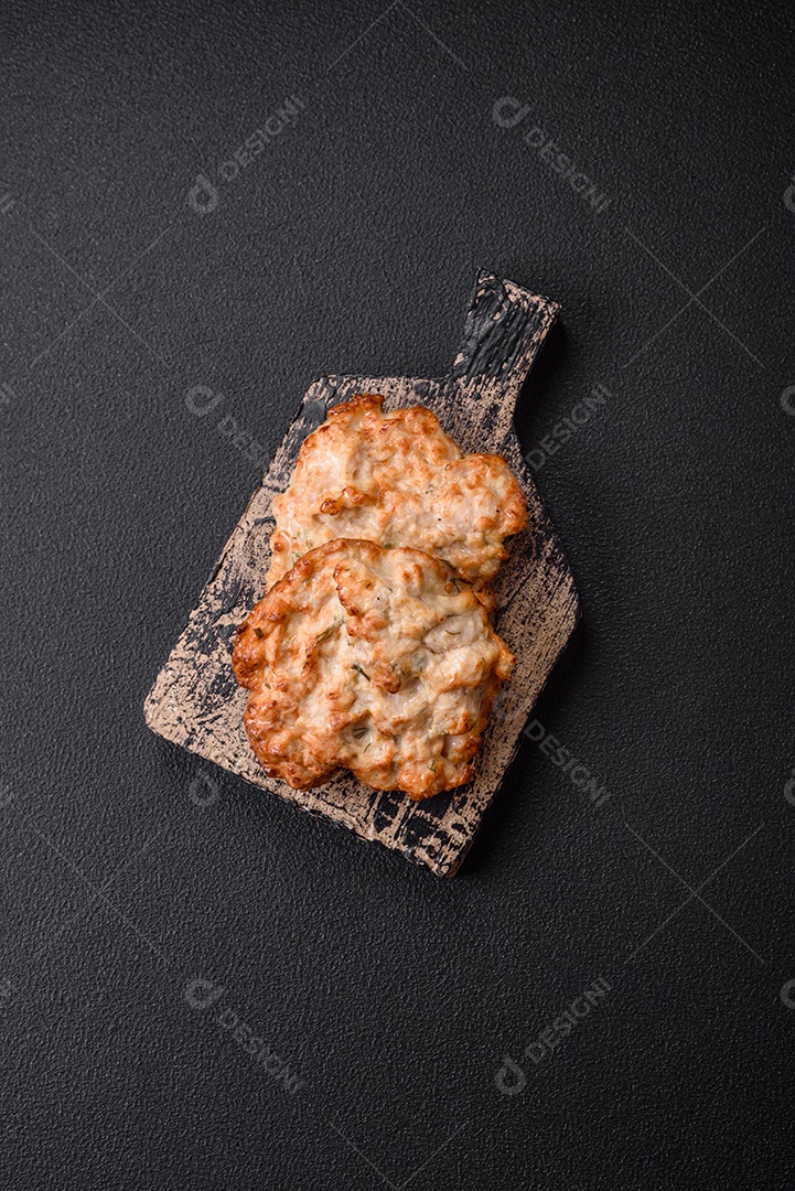 Deliciosa costeleta de frango frito ou carne de porco frita à milanesa com sal, especiarias e ervas sobre um fundo escuro de concreto