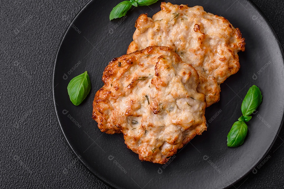 Deliciosa costeleta de frango frito ou carne de porco frita à milanesa com sal, especiarias e ervas sobre um fundo escuro de concreto