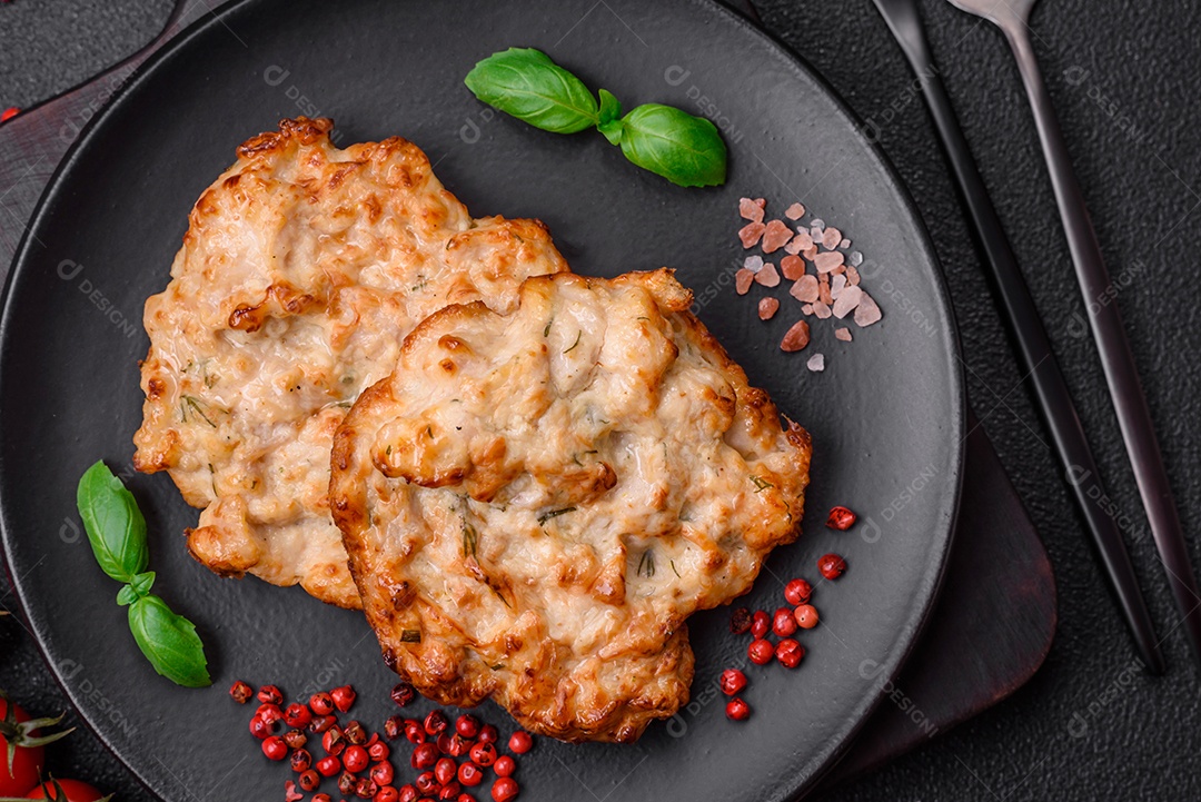 Deliciosa costeleta de frango frito ou carne de porco frita à milanesa com sal, especiarias e ervas sobre um fundo escuro de concreto
