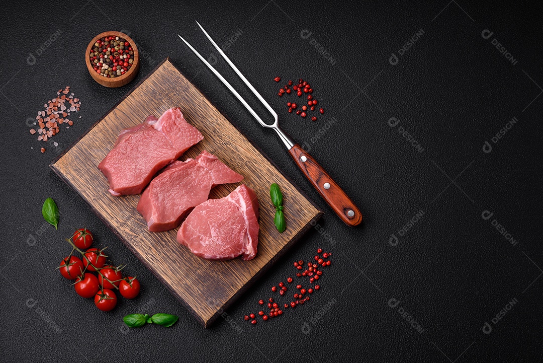 Bife de carne de porco fresca crua com sal, especiarias e ervas numa tábua de madeira