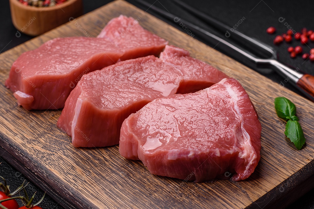 Carne de peru crua em forma de fatias com sal, especiarias e ervas sobre um fundo escuro de concreto