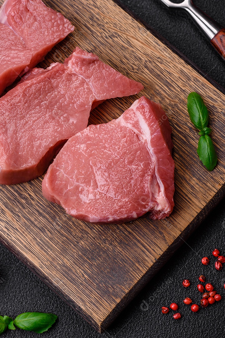 Carne de peru crua em forma de fatias com sal, especiarias e ervas sobre um fundo escuro de concreto