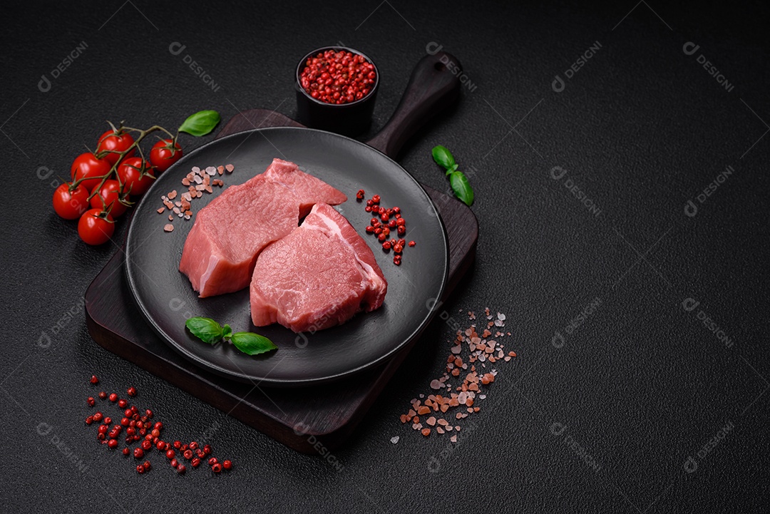 Bife de carne de porco fresca crua com sal, especiarias e ervas numa tábua de madeira