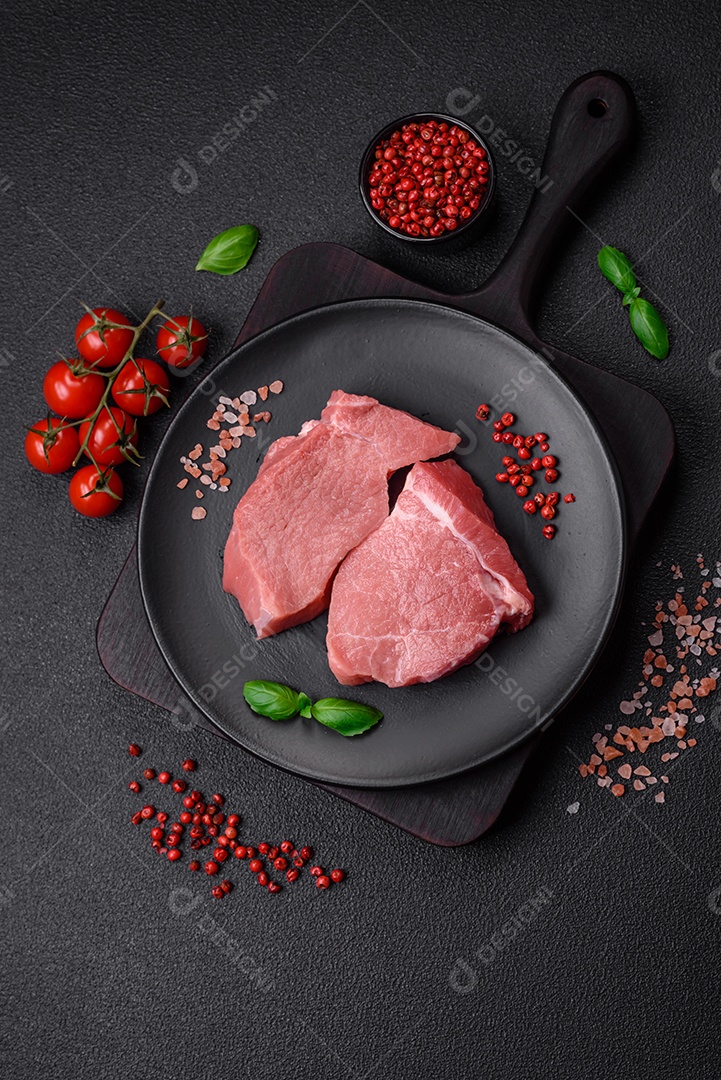 Bife de carne de porco fresca crua com sal, especiarias e ervas numa tábua de madeira