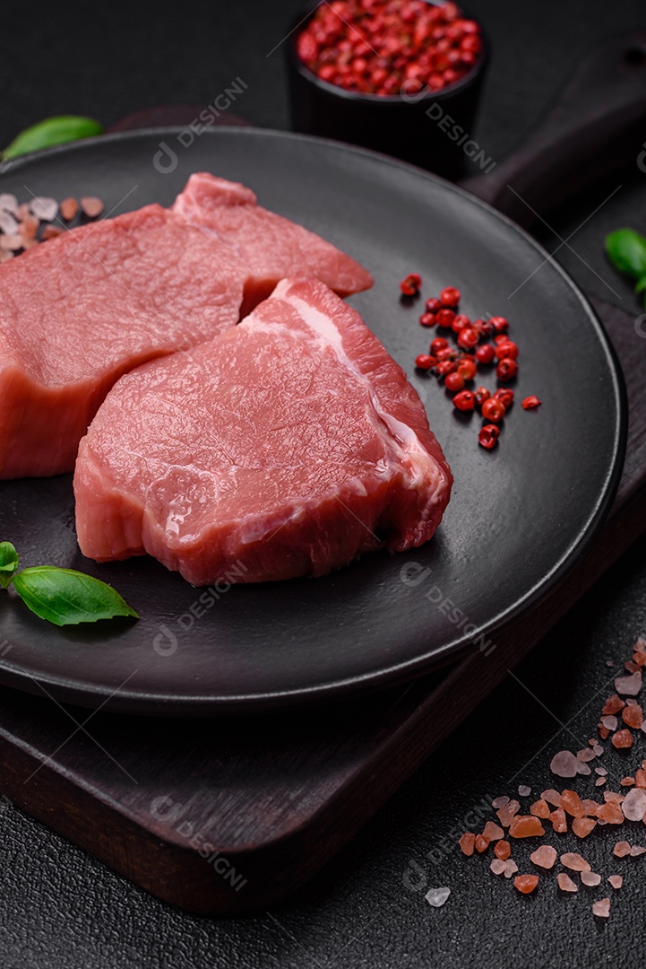 Carne de peru crua em forma de fatias com sal, especiarias e ervas sobre um fundo escuro de concreto