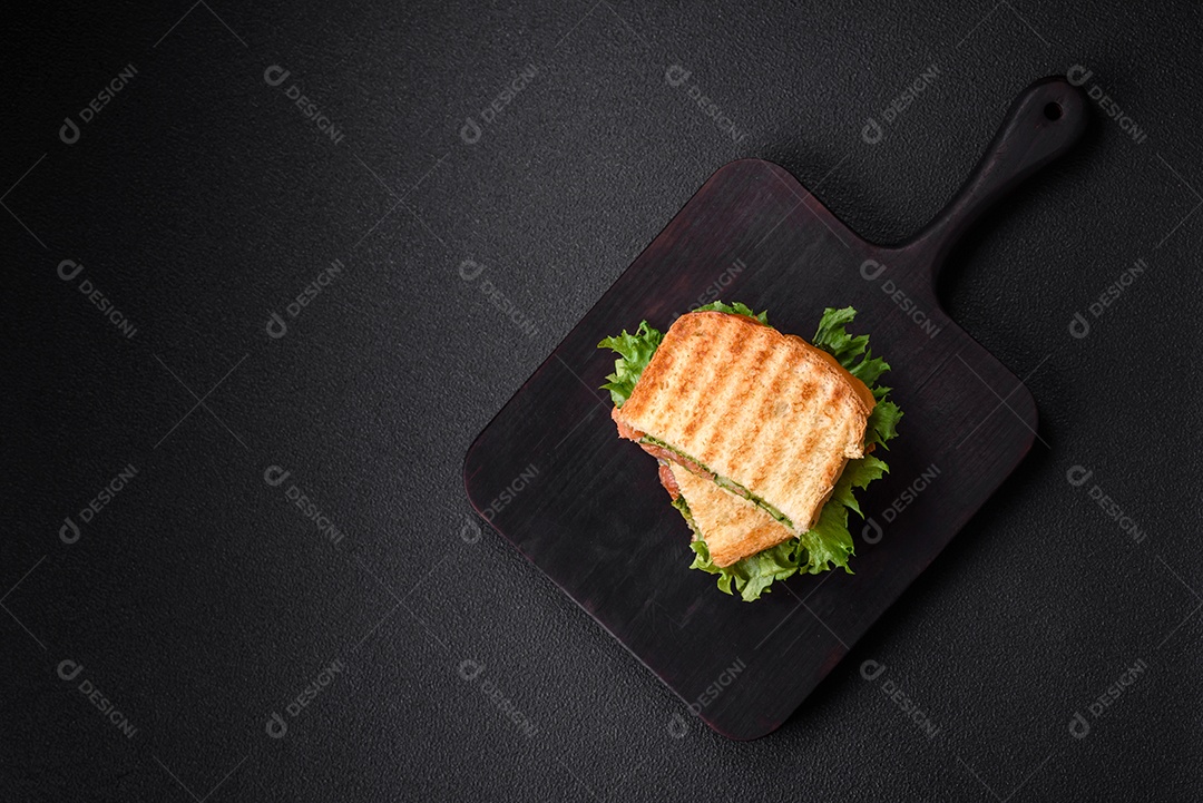 Delicioso sanduíche crocante com torradas, salmão, abacate, tomate, sal, especiarias e ervas sobre um fundo escuro de concreto