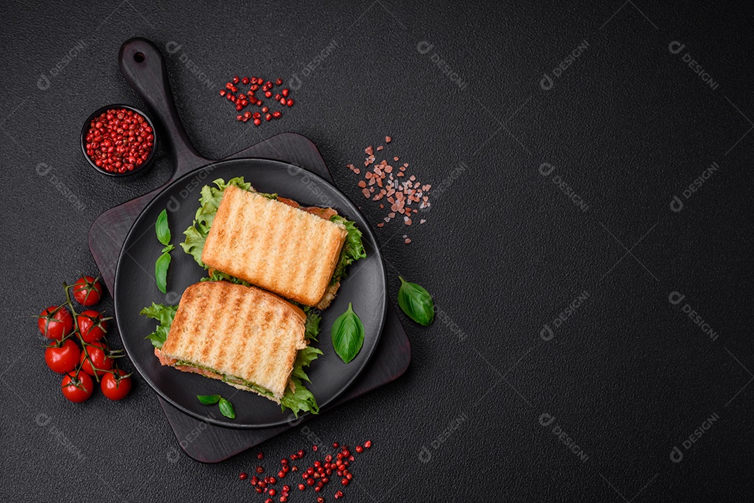 Delicioso sanduíche crocante com torradas, salmão, abacate, tomate, sal, especiarias e ervas sobre um fundo escuro de concreto