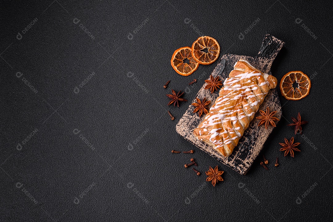 Delicioso pão trançado crocante com passas dentro e glacê branco fora sobre um fundo escuro de concreto