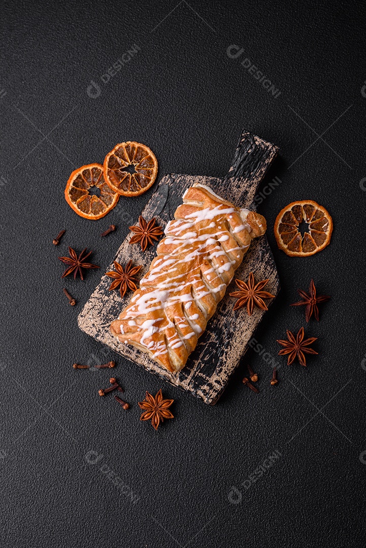 Delicioso pão trançado crocante com passas dentro e glacê branco fora sobre um fundo escuro de concreto