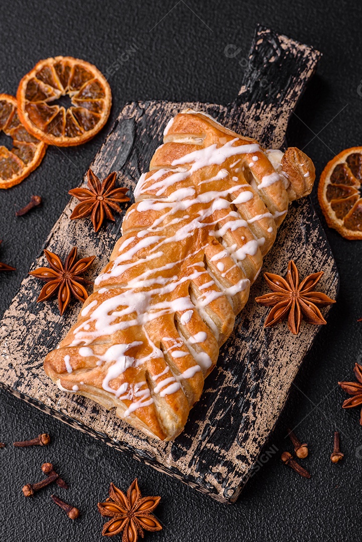 Delicioso pão trançado crocante com passas dentro e glacê branco fora sobre um fundo escuro de concreto