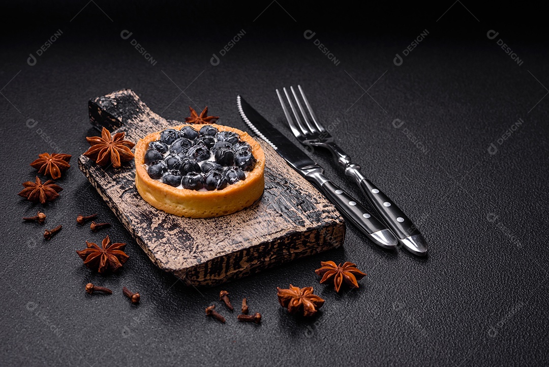 Deliciosa torta redonda doce e fresca com mirtilos maduros e creme sobre um fundo escuro de concreto
