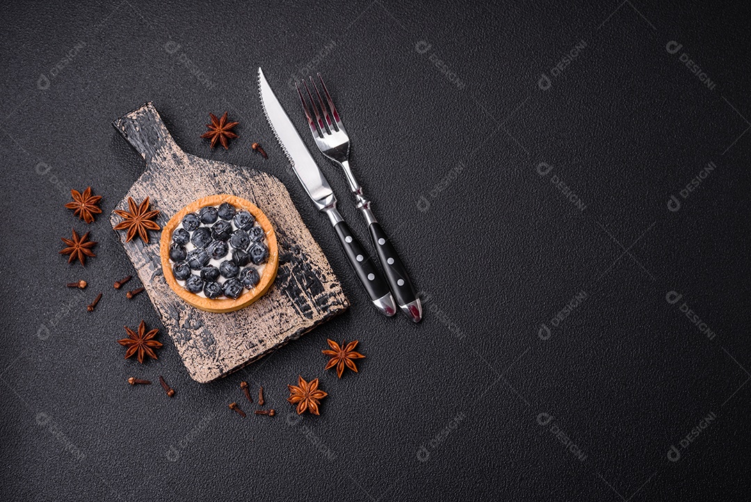 Deliciosa torta redonda doce e fresca com mirtilos maduros e creme sobre um fundo escuro de concreto