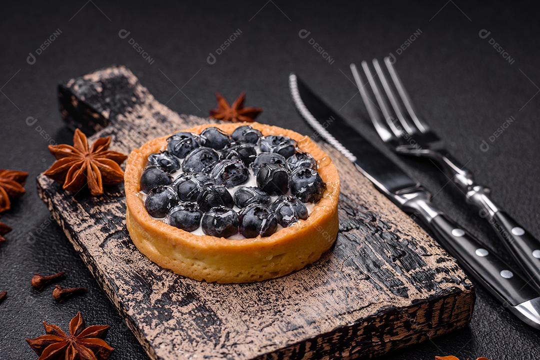 Deliciosa torta redonda doce e fresca com mirtilos maduros e creme sobre um fundo escuro de concreto