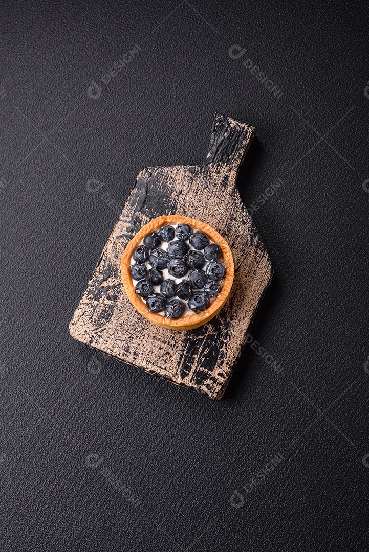 Deliciosa torta redonda doce e fresca com mirtilos maduros e creme sobre um fundo escuro de concreto
