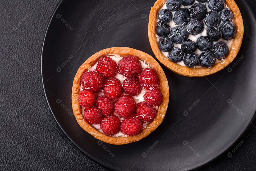 Deliciosa torta redonda doce e fresca com mirtilos maduros e creme sobre um fundo escuro de concreto