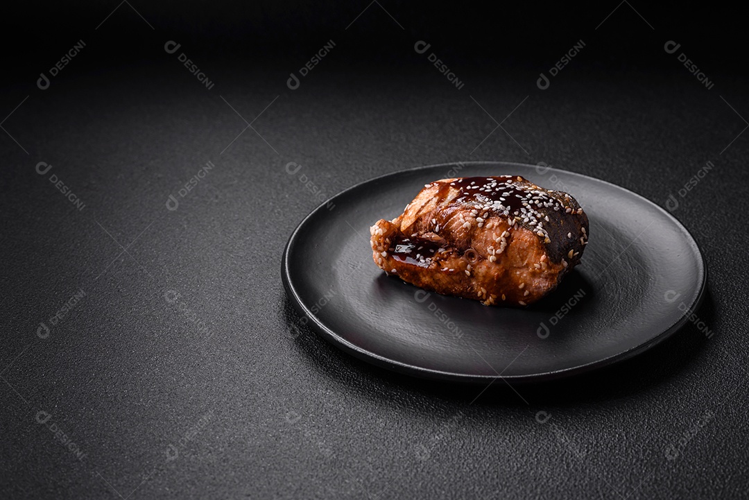 Delicioso frango frito suculento com molho teriyaki agridoce e sementes de gergelim em um fundo escuro de concreto