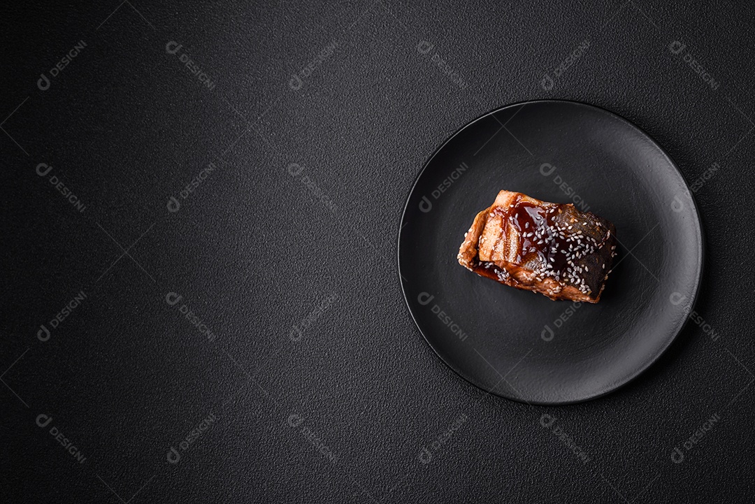 Delicioso filé de salmão grelhado com sal, especiarias, ervas e molho sobre fundo escuro de concreto