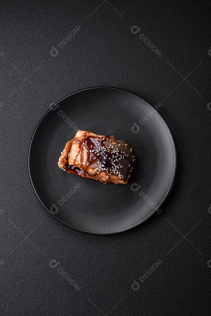 Delicioso filé de salmão grelhado com sal, especiarias, ervas e molho sobre fundo escuro de concreto