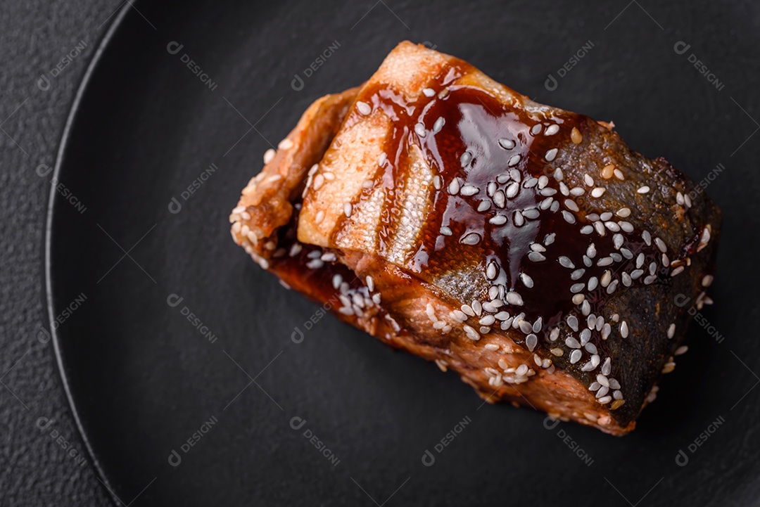 Delicioso filé de salmão grelhado com sal, especiarias, ervas e molho sobre fundo escuro de concreto