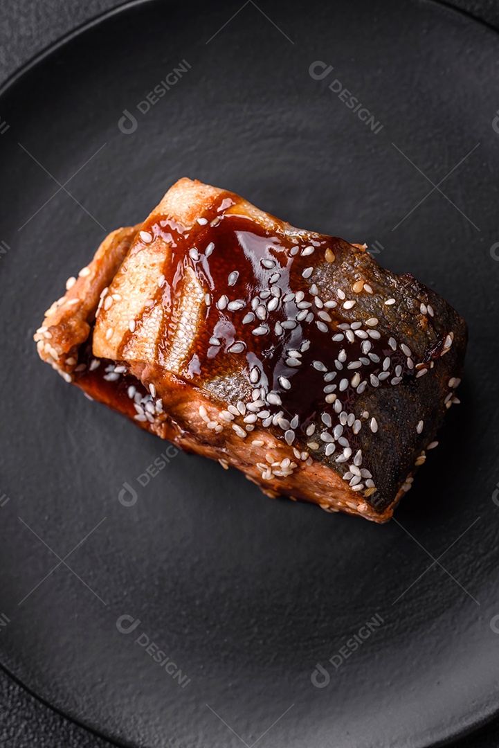 Delicioso filé de salmão grelhado com sal, especiarias, ervas e molho sobre fundo escuro de concreto