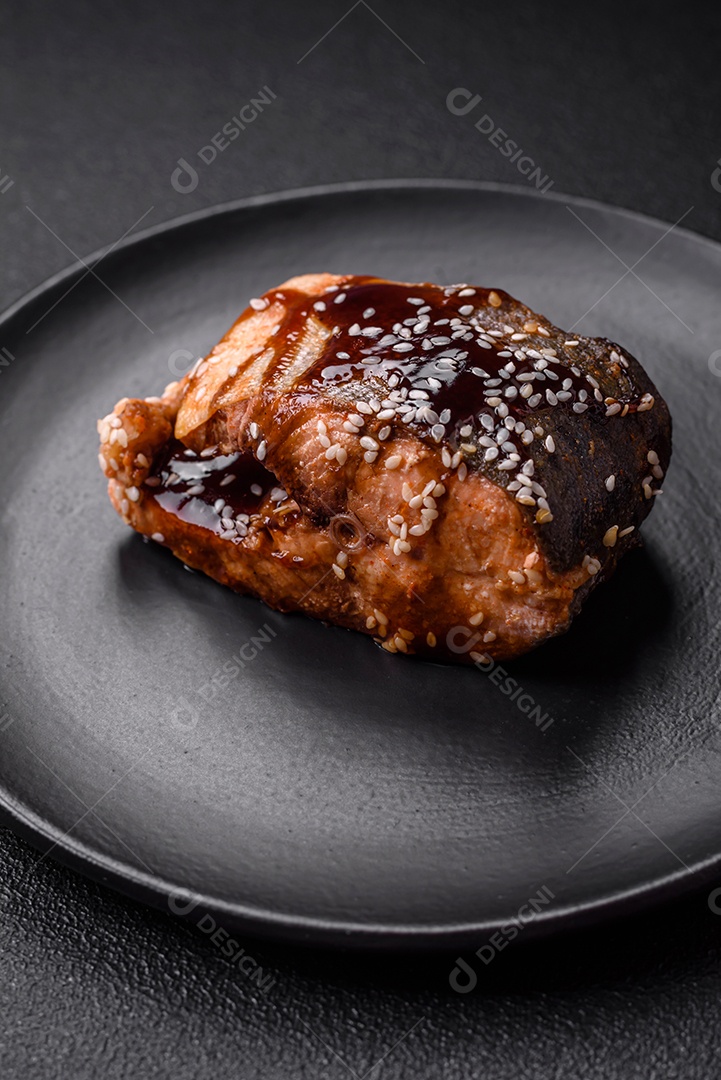 Delicioso filé de salmão grelhado com sal, especiarias, ervas e molho sobre fundo escuro de concreto