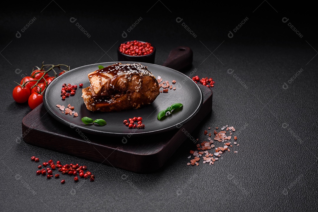 Delicioso filé de salmão grelhado com sal, especiarias, ervas e molho sobre fundo escuro de concreto