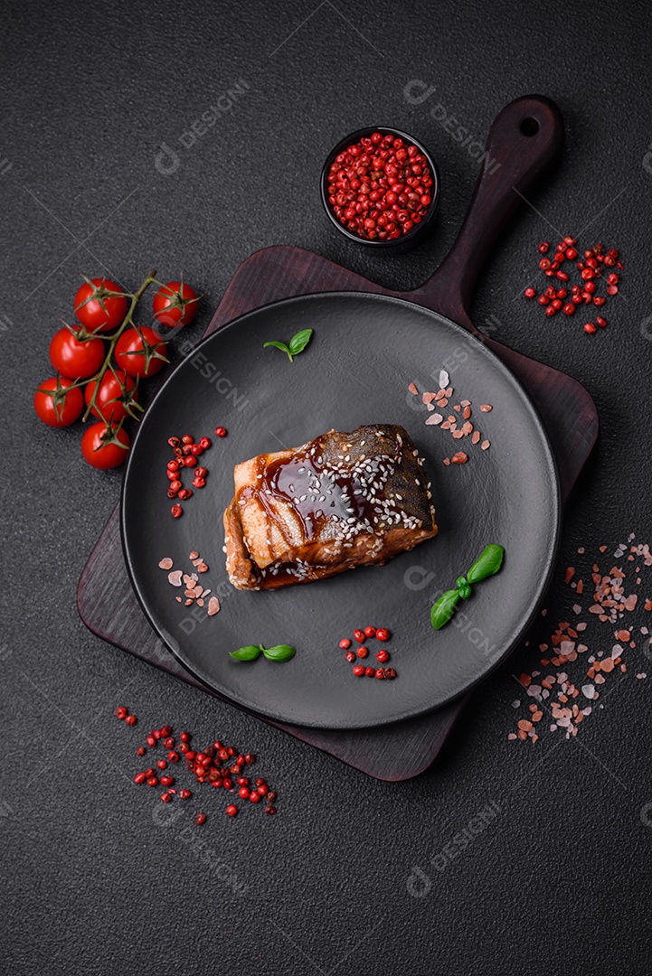 Delicioso filé de salmão grelhado com sal, especiarias, ervas e molho sobre fundo escuro de concreto