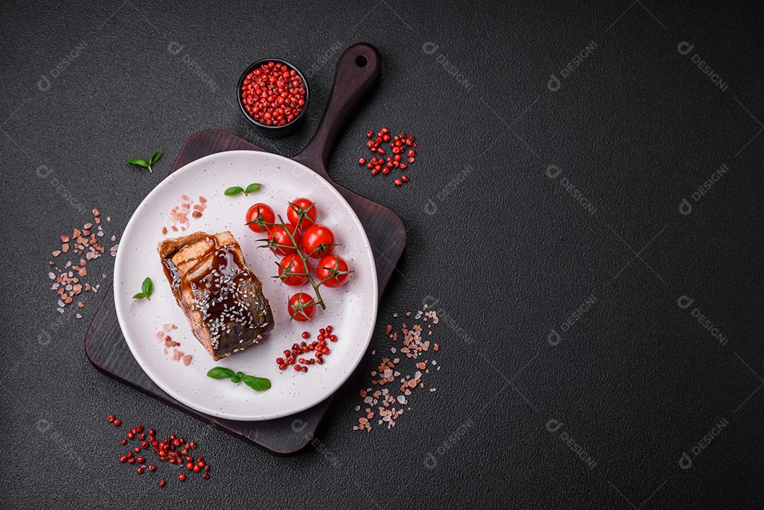 Delicioso filé de salmão grelhado com sal, especiarias, ervas e molho sobre fundo escuro de concreto