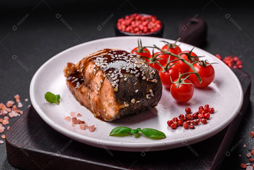 Delicioso filé de salmão grelhado com sal, especiarias, ervas e molho sobre fundo escuro de concreto