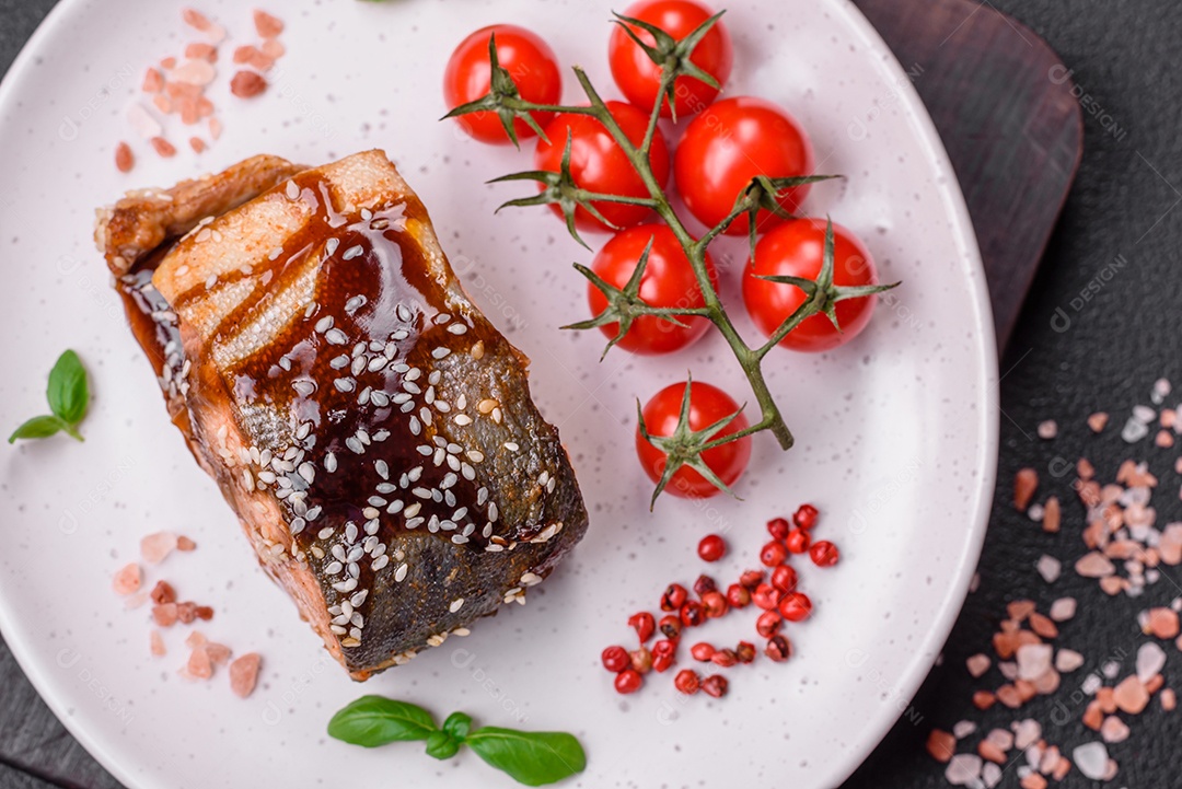 Delicioso filé de salmão grelhado com sal, especiarias, ervas e molho sobre fundo escuro de concreto