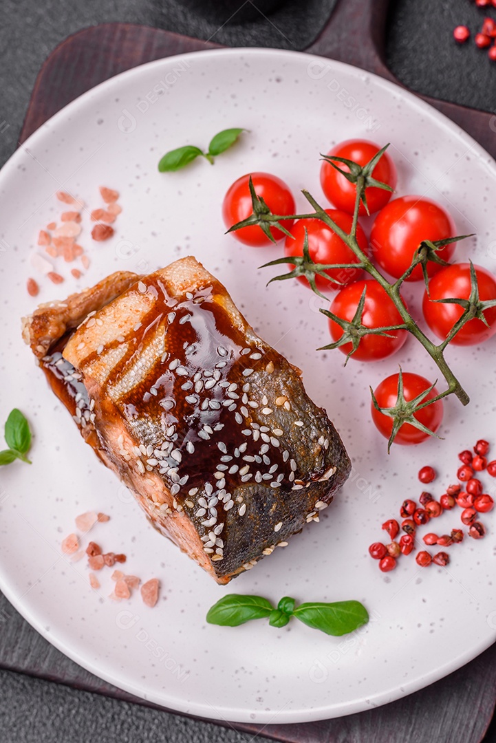 Delicioso filé de salmão grelhado com sal, especiarias, ervas e molho sobre fundo escuro de concreto