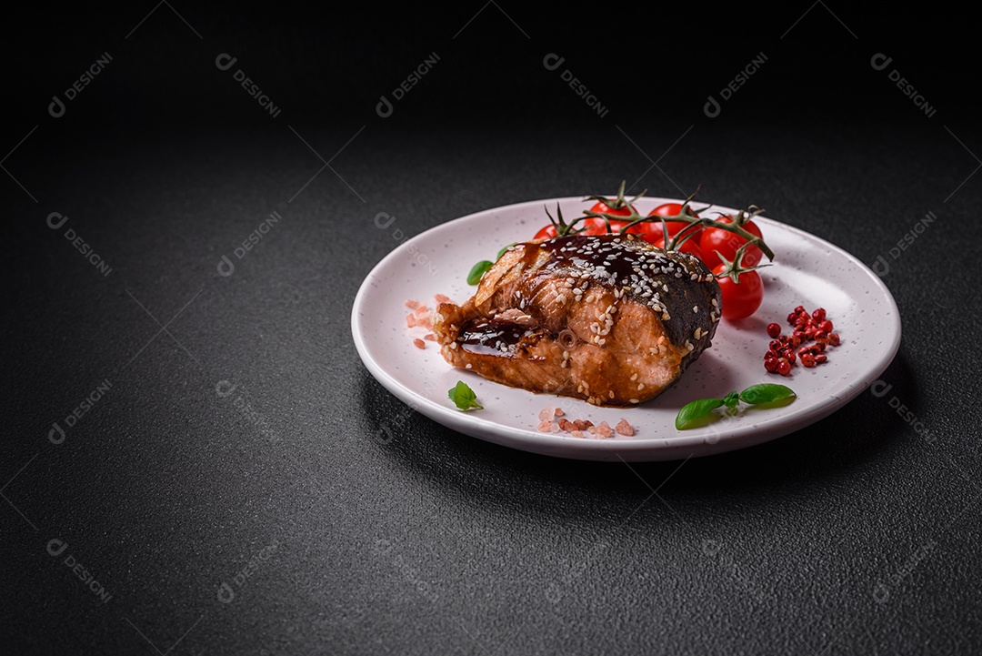 Delicioso filé de salmão grelhado com sal, especiarias, ervas e molho sobre fundo escuro de concreto