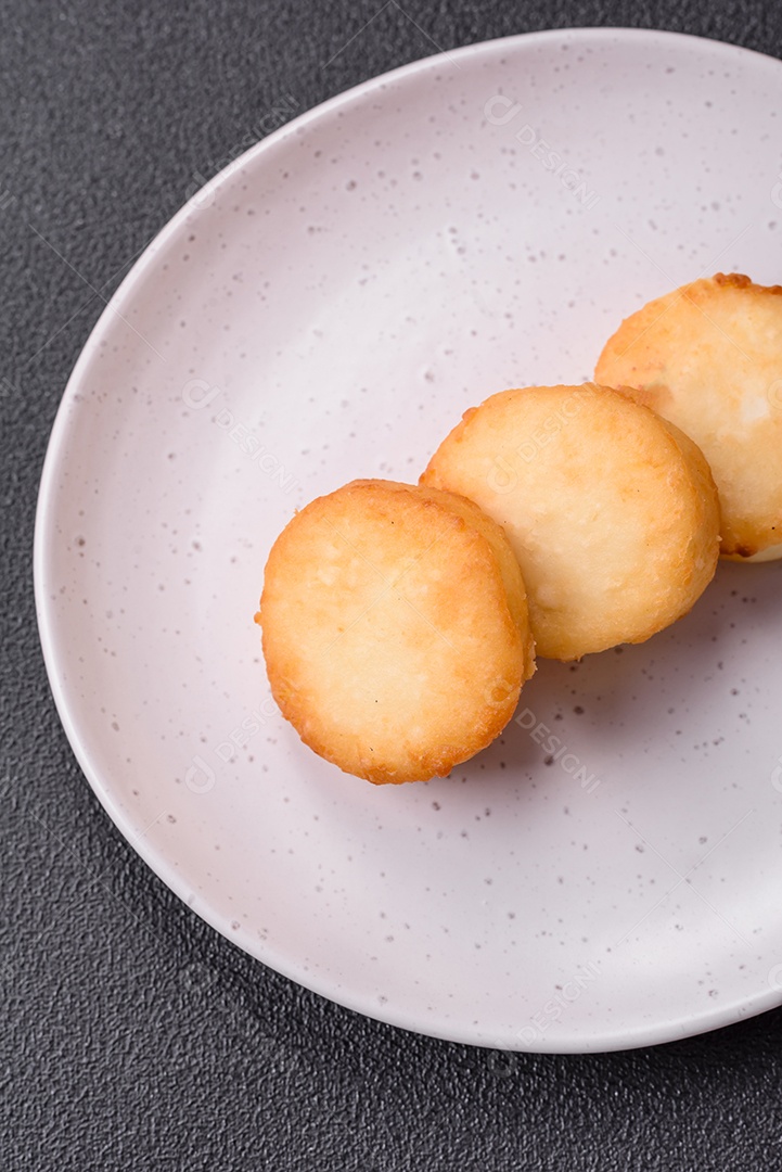 Deliciosas panquecas de queijo doce fresco com passas e canela num prato de cerâmica