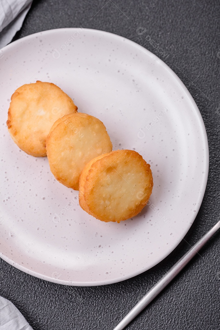 Deliciosas panquecas de queijo doce fresco com passas e canela num prato de cerâmica