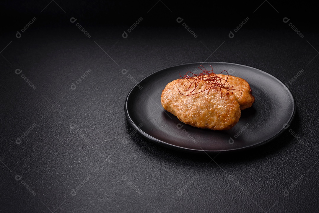 Deliciosas costeletas ou almôndegas fritas com sal, especiarias e ervas sobre um fundo escuro de concreto