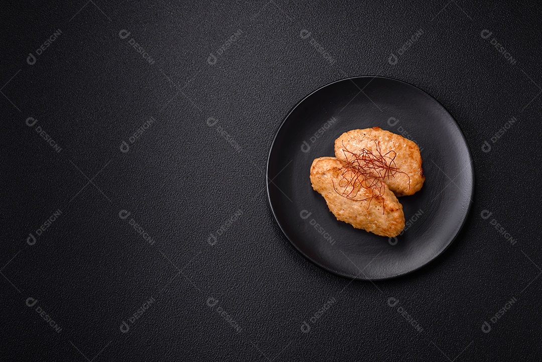 Deliciosas costeletas ou almôndegas fritas com sal, especiarias e ervas sobre um fundo escuro de concreto