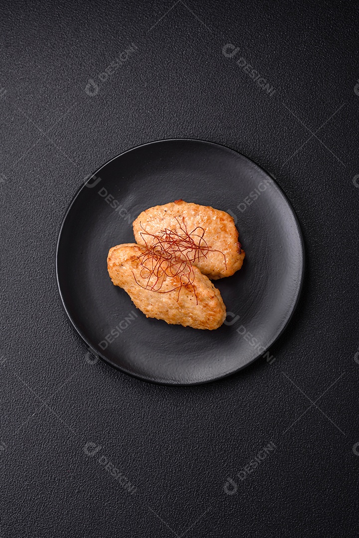 Deliciosas costeletas ou almôndegas fritas com sal, especiarias e ervas sobre um fundo escuro de concreto