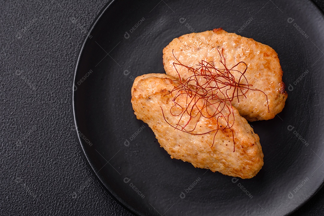 Deliciosas costeletas ou almôndegas fritas com sal, especiarias e ervas sobre um fundo escuro de concreto