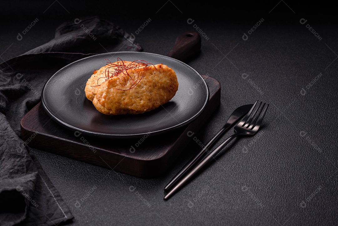 Deliciosas costeletas ou almôndegas fritas com sal, especiarias e ervas sobre um fundo escuro de concreto