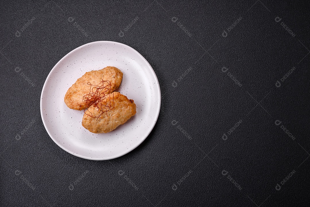 Deliciosas costeletas ou almôndegas fritas com sal, especiarias e ervas sobre um fundo escuro de concreto