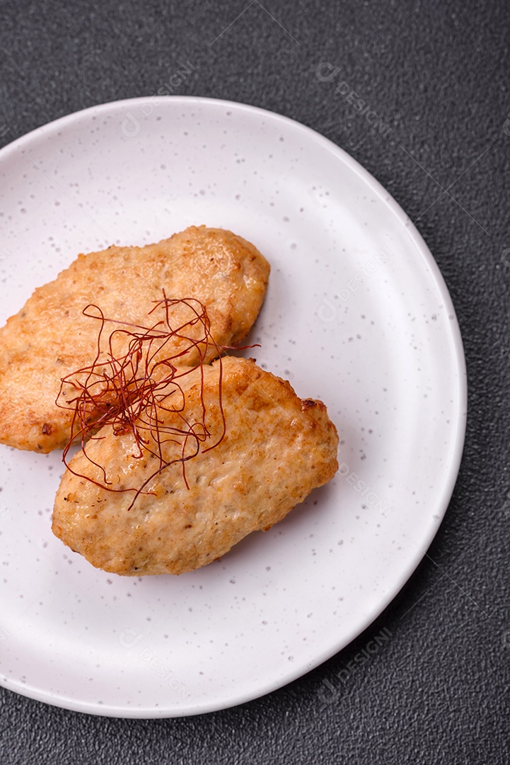 Deliciosas costeletas ou almôndegas fritas com sal, especiarias e ervas sobre um fundo escuro de concreto