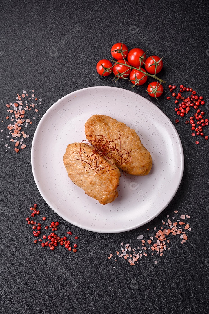 Deliciosas costeletas ou almôndegas fritas com sal, especiarias e ervas sobre um fundo escuro de concreto