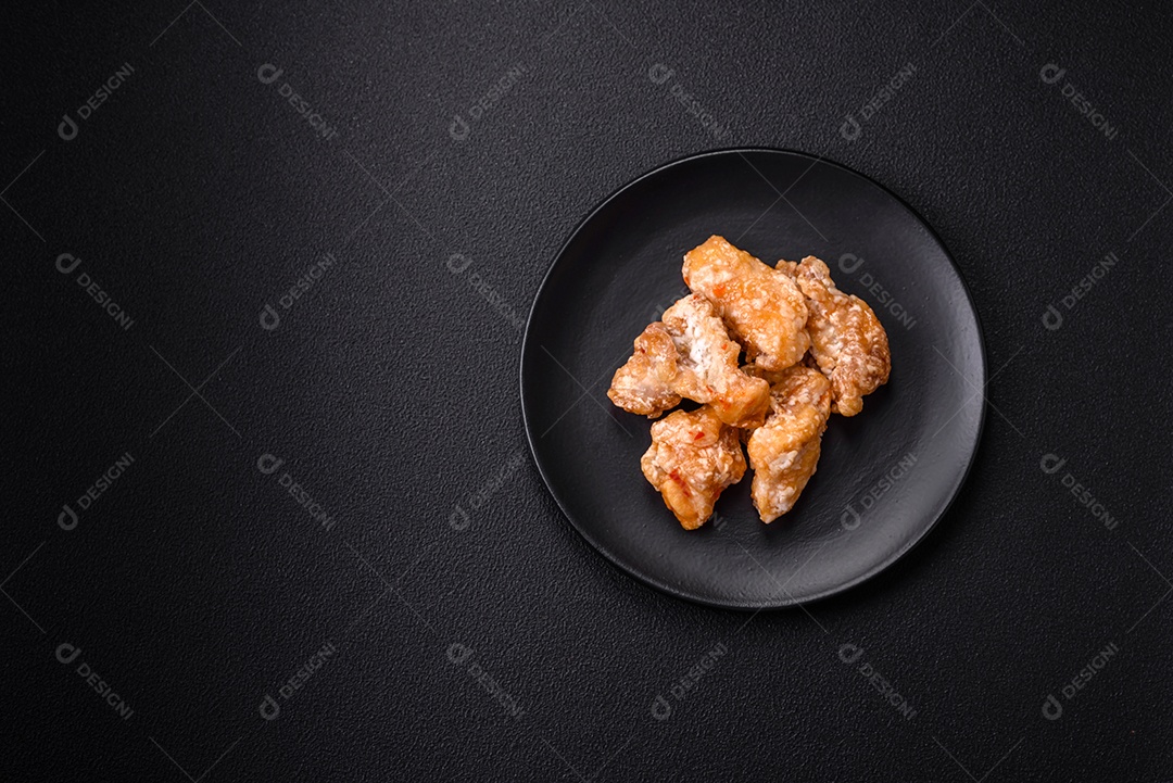 Deliciosos suculentos pedaços de frango grelhado em molho agridoce com sal e especiarias num prato cerâmico