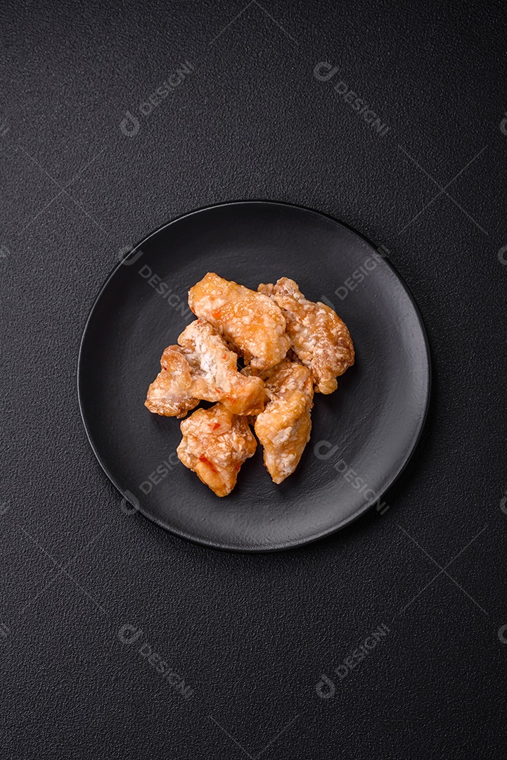 Deliciosos suculentos pedaços de frango grelhado em molho agridoce com sal e especiarias num prato cerâmico