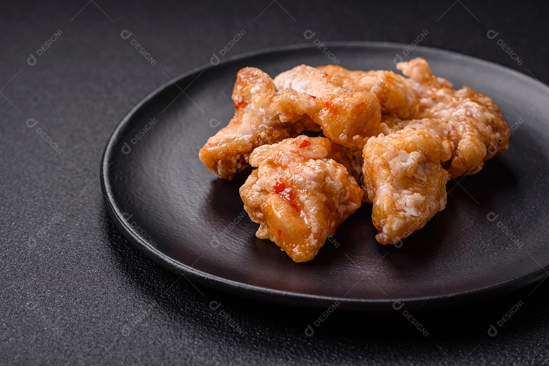 Deliciosos suculentos pedaços de frango grelhado em molho agridoce com sal e especiarias num prato cerâmico