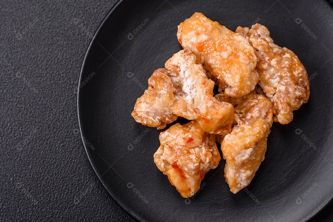 Deliciosos suculentos pedaços de frango grelhado em molho agridoce com sal e especiarias num prato cerâmico