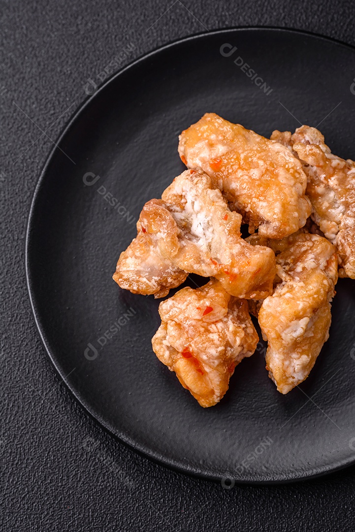 Deliciosos suculentos pedaços de frango grelhado em molho agridoce com sal e especiarias num prato cerâmico