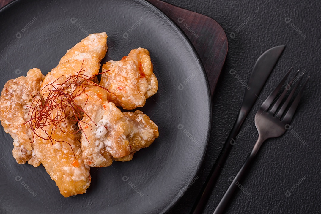 Deliciosos suculentos pedaços de frango grelhado em molho agridoce com sal e especiarias num prato cerâmico