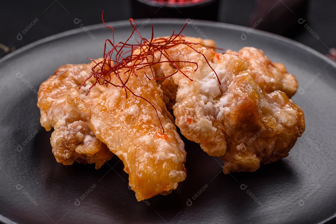 Deliciosos suculentos pedaços de frango grelhado em molho agridoce com sal e especiarias num prato cerâmico